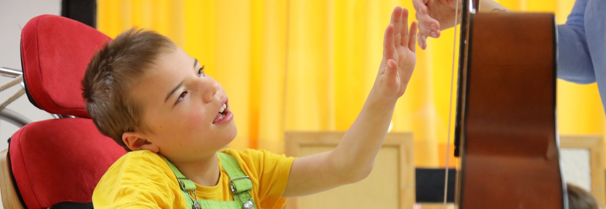 Junge mit Hörsehbehinderung greift nach Hand einer Lehrerin