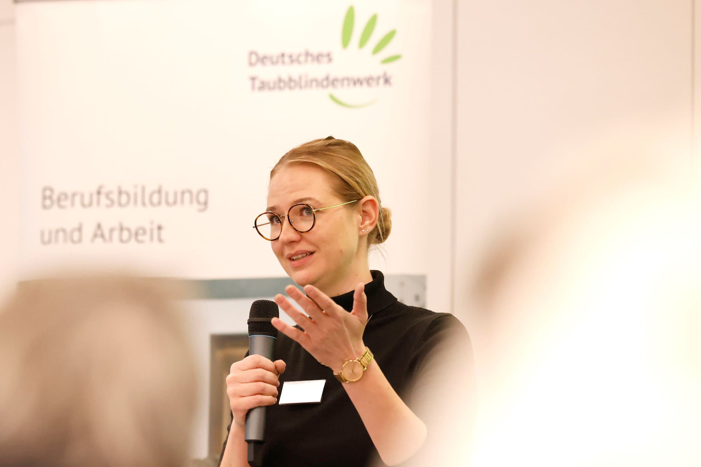 Frau mit Brille hält ein Mikrophon in der Hand