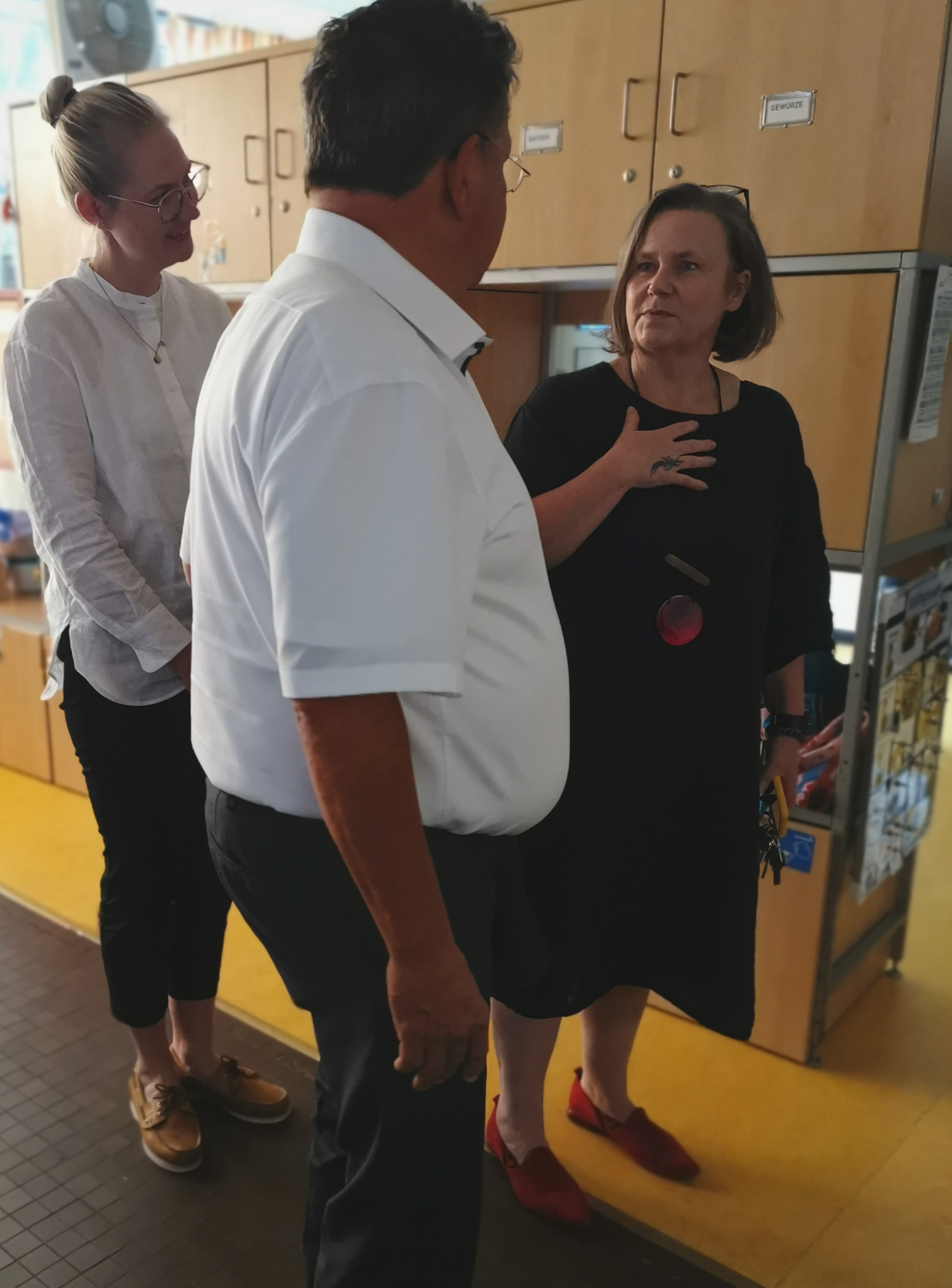 ein Mann und zwei Frauen stehen im Halbkreis nebeneinander und tauschen sich intensiv aus